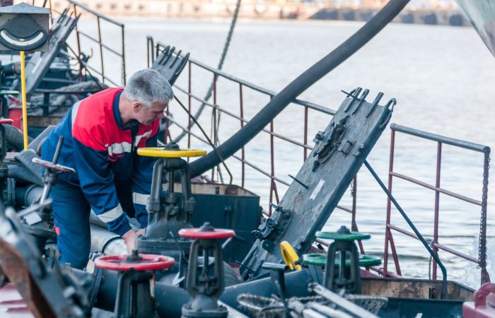 Russia, St. Petersburg, May 2021: A worker in a marine uniform on the deck of an oil tanker in the bay in the port
